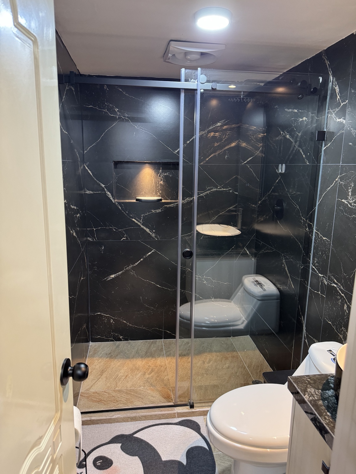 Shower with a glass enclosure and dark wall finishes
