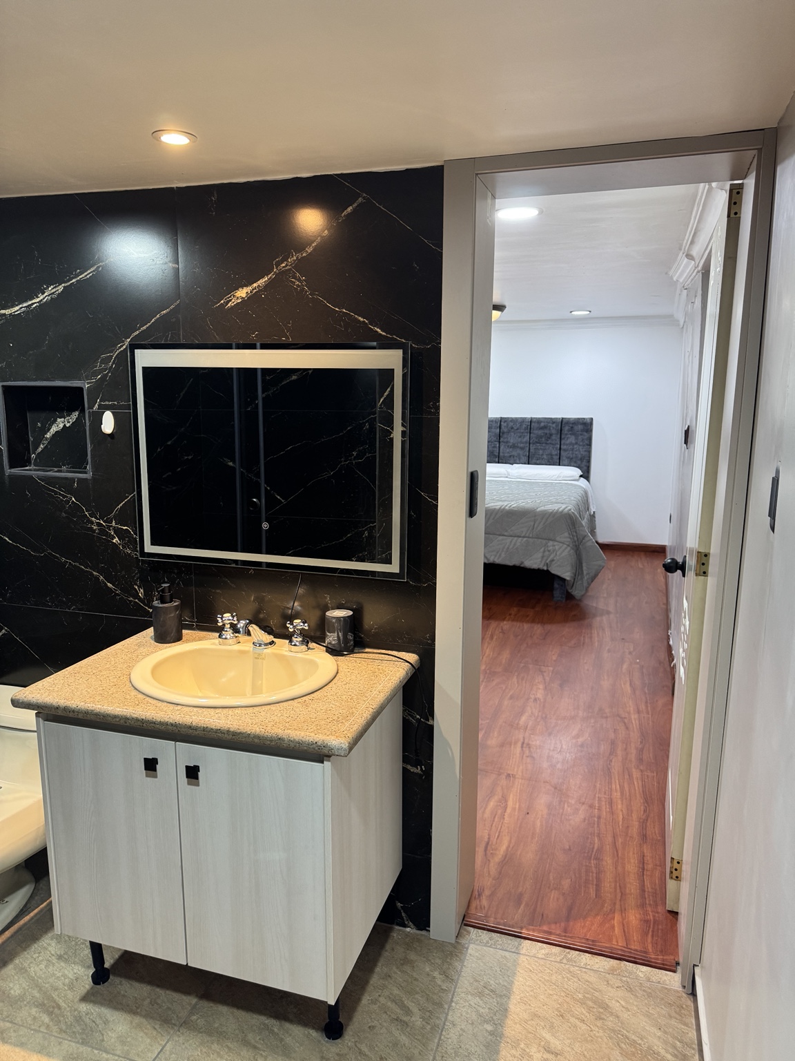 Basin and mirror with a view towards the bedroom