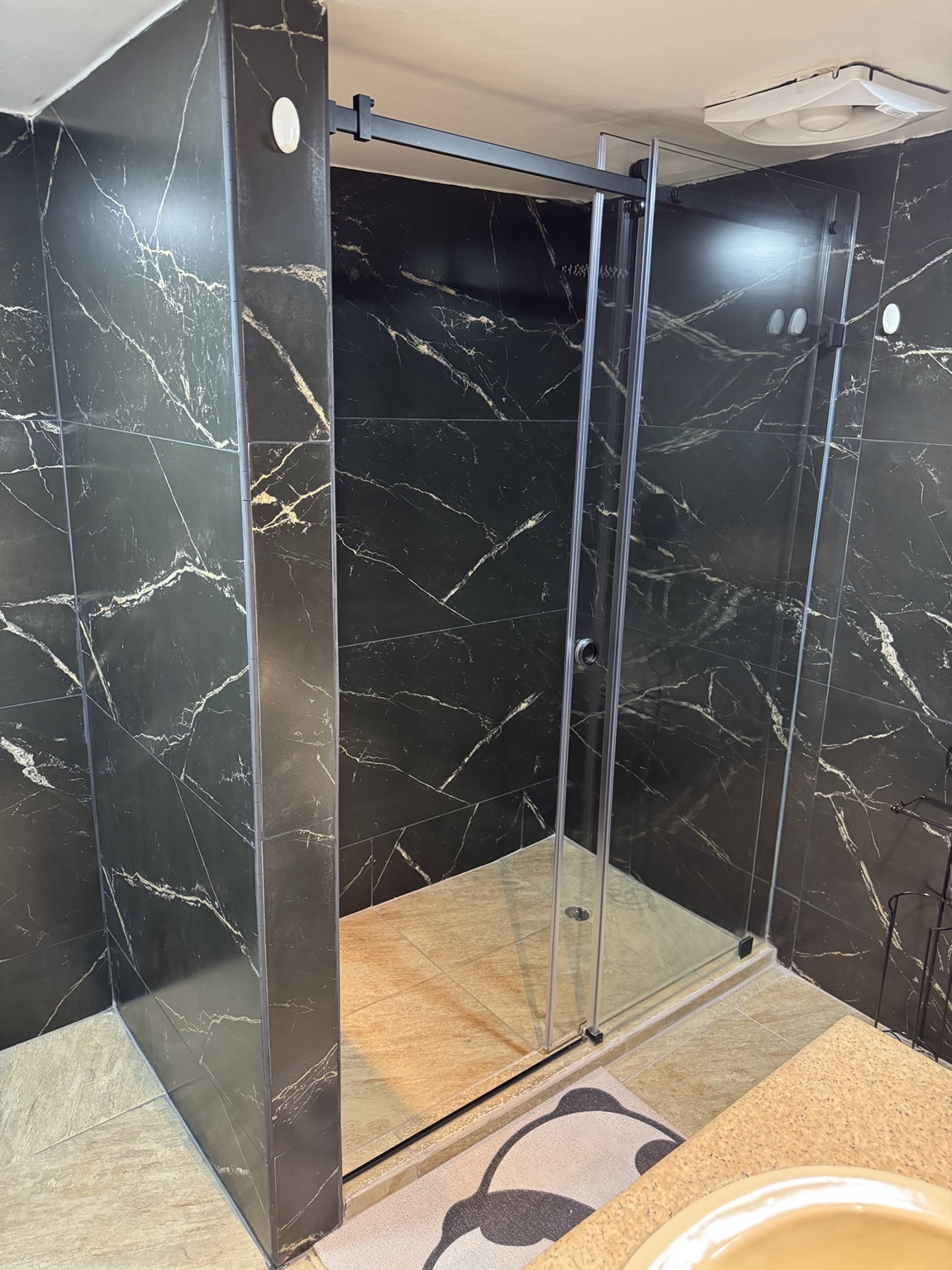 Shower with a glass enclosure and dark wall finishes
